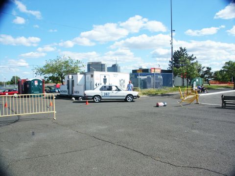 2001 Mercury Grand Marquis - A white sedan is parked next to portable restrooms under a partly cloudy sky.