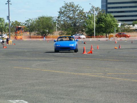 2001 Mercury Grand Marquis - A blue convertible navigates a cone course in a large paved area with buildings and trees in the background.