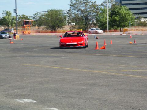 2001 Mercury Grand Marquis - A red sports car navigates a course marked by orange cones on a sunny day.