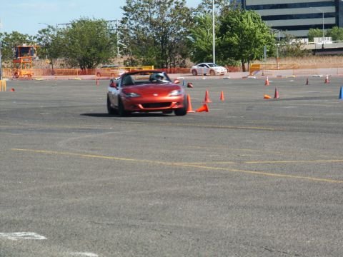 2001 Mercury Grand Marquis - Orange convertible sports car navigates a course marked by traffic cones, with another vehicle visible in the distance.