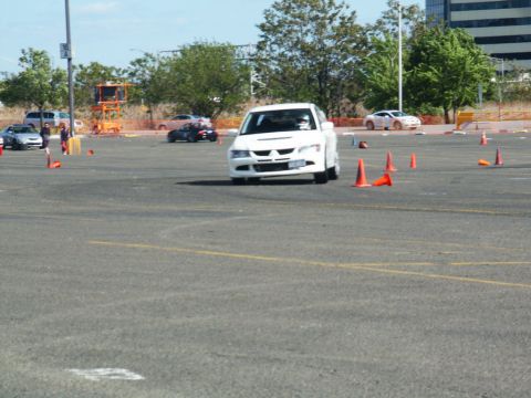 2001 Mercury Grand Marquis - A white Mitsubishi Lancer Evolution navigates a course marked by traffic cones on a sunny day.