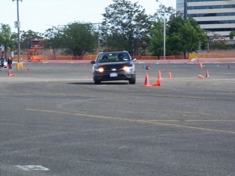 2001 Mercury Grand Marquis - A dark SUV maneuvers through a cone course on a paved lot, with buildings and trees in the background.