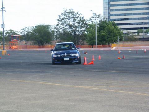 2001 Mercury Grand Marquis - A blue BMW M3 navigates a course marked by orange cones in an open lot.
