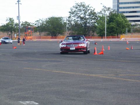 2001 Mercury Grand Marquis - A red convertible sports car navigates a course marked by orange cones on a paved lot.