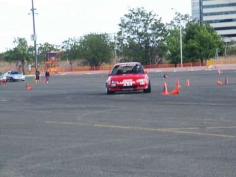 2001 Mercury Grand Marquis - A red car with racing decals is seen on a cone course, with another car visible in the background.