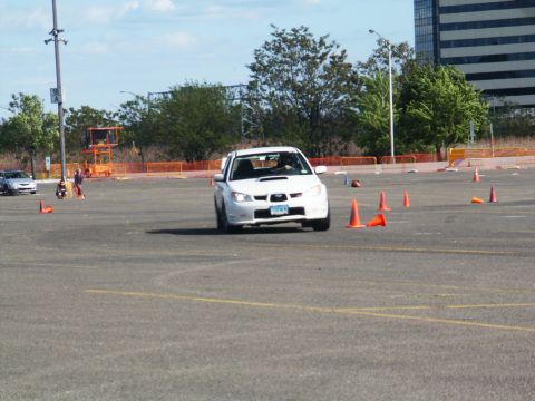 2001 Mercury Grand Marquis - A white Subaru Impreza WRX navigates an autocross course with orange cones marking the path.
