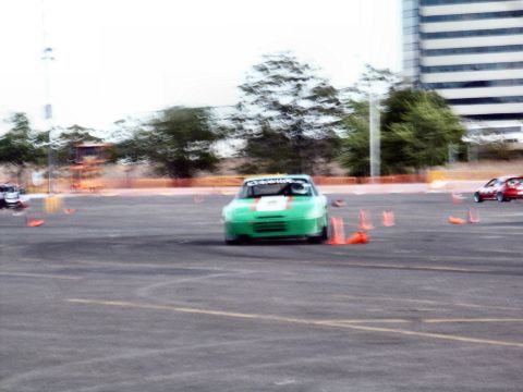 2001 Mercury Grand Marquis - A green race car navigates a course marked by orange cones, with another vehicle in the distance.