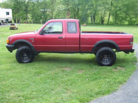 1996 Ford Bronco - Side view of a red pickup truck, identified as a Ranger V6 by its badge.
