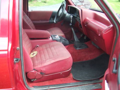 1996 Ford Bronco - The interior of a red pickup truck features cloth seats and a manual transmission shifter.