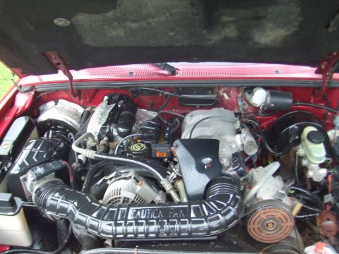 1996 Ford Bronco - The engine bay of a red vehicle is shown, with a prominent air intake tube bearing a "CAUTION FAN" warning.