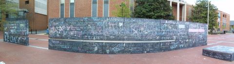 1971 Ford Ranchero - A panoramic view captures a large, curved wall adorned with extensive chalk graffiti, set within a brick-paved outdoor space.