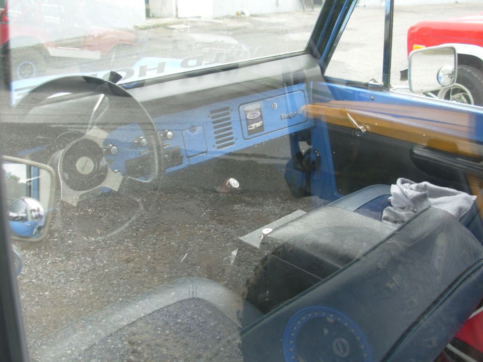 Blue early Ford Bronco interior with Ranger-badged dash and vinyl bucket seats, doors removed