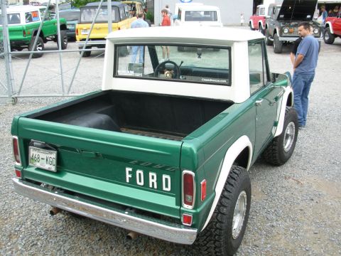 1975 Ford Bronco - Green 1975 Ford Bronco with a white hardtop and a Tennessee license plate is seen from the rear at an outdoor event.