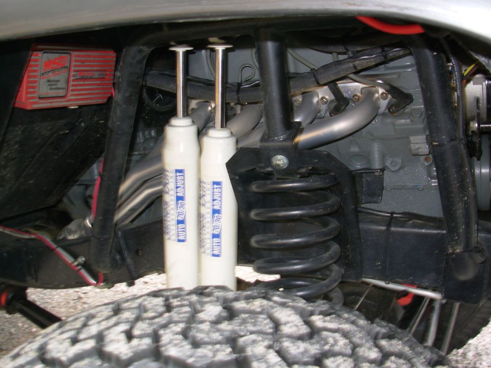 Dual white shocks, black coil spring and red MSD ignition box in a lifted 4x4 wheel well