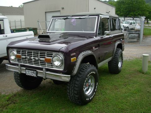 1975 Ford Bronco - A classic 1975 Ford Bronco is shown with a prominent hood scoop and off-road tires.