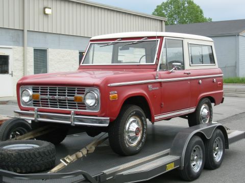 1975 Ford Bronco - A red 1975 Ford Bronco is loaded onto a trailer, ready for transport.