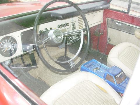 1975 Ford Bronco - Interior view of a 1975 Ford Bronco, beige seats and a blue toy truck on the passenger side.