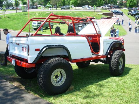 1975 Ford Bronco - Modified 1975 Ford Bronco with custom roll cage and off-road tires displayed at an event.