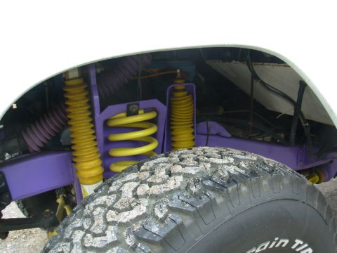 1975 Ford Bronco - Custom suspension components, including yellow shocks and springs, are visible on this vehicle, alongside an off-road tire.