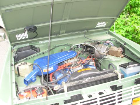 1975 Ford Bronco - The engine compartment of a classic Ford Bronco is open, revealing its V8 engine and associated components.