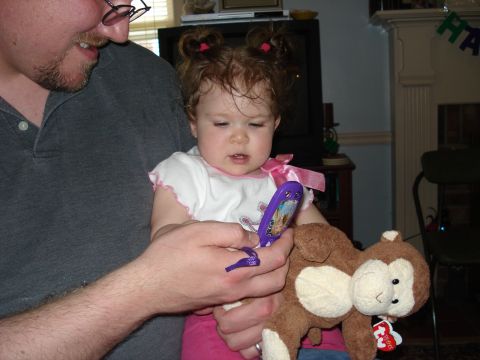 2000 Ford Crown Victoria - A baby girl with pigtails looks at a toy phone while holding a stuffed monkey.