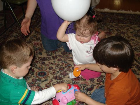 2000 Ford Crown Victoria - Children engage in playtime with toys and a balloon on a carpeted floor.