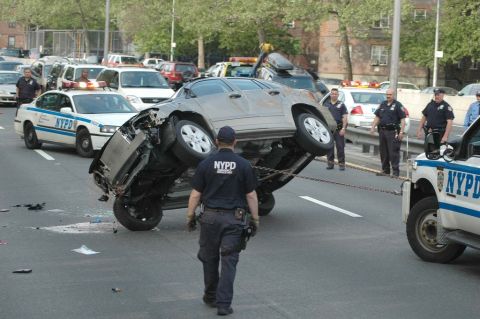 1991 Ford Crown Victoria - Accident scene with an overturned vehicle being secured by NYPD officers and tow truck.