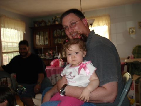 2000 Ford Crown Victoria - A man holds a baby while another man stands in the background near a window. The scene appears to be indoors, possibly a dining room.