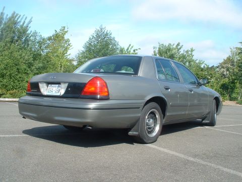 2000 Ford Crown Victoria - This gray 2000 Ford Crown Victoria sedan is viewed from the rear 3/4 angle in a parking lot.