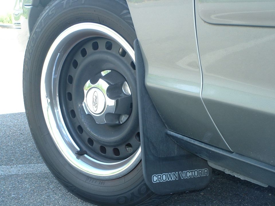 Close-up of a Ford Crown Victoria's front passenger wheel, tire, and mud flap.