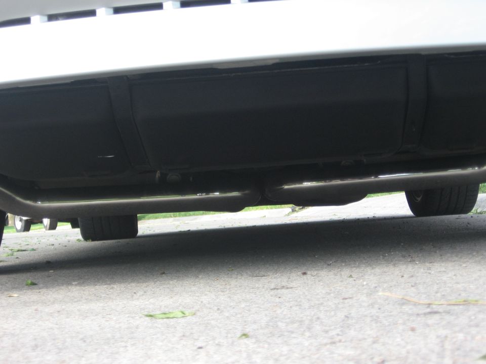 Underside of a car showing dual exhaust pipes and fuel tank.