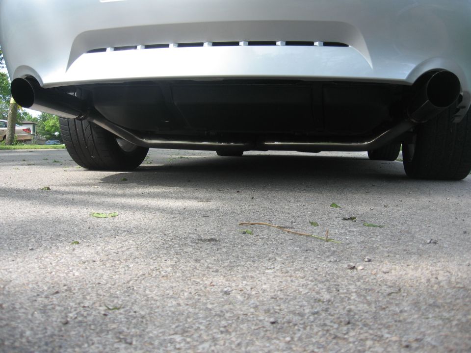 Rear underside of a silver sedan with dual exhaust pipes and tires.