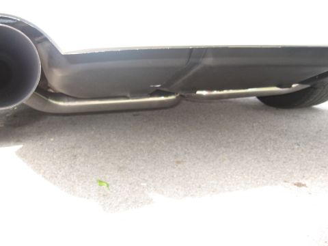 1998 Ford Taurus - A low-angle, close-up shot of the rear underside of a white vehicle, focusing on the exhaust system and a portion of the rear bumper. The e…