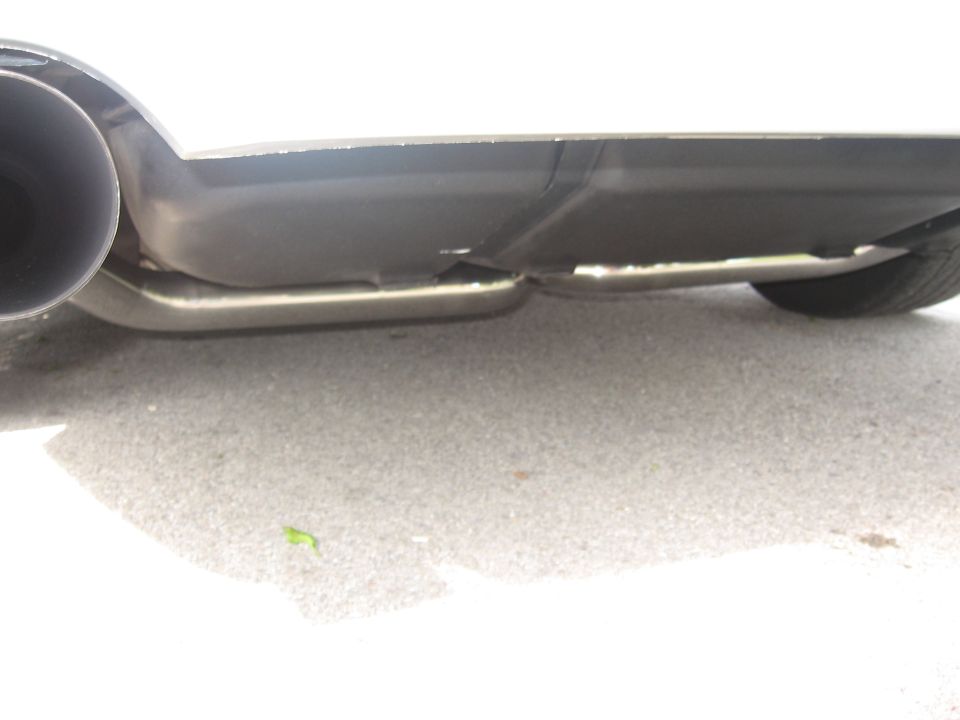 Underside of a white vehicle showing exhaust pipe and rear diffuser.