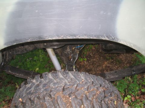 1979 Ford Bronco - The underside of a vehicle's fender well is shown, with a large off-road tire in the foreground. Visible components include a leaf spring s…