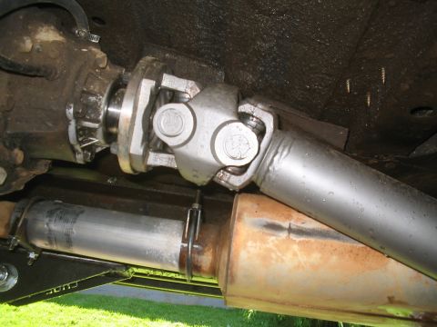 1979 Ford Bronco - The underside of a vehicle shows a driveshaft connected to a transfer case, with a section of the exhaust system visible below. The vehicle…