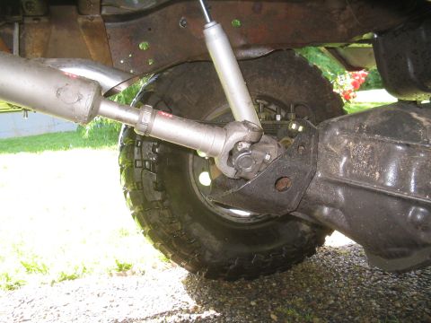 1979 Ford Bronco - A close-up view of the rear axle, driveshaft, and exhaust system of a vehicle, likely a 1979 Ford Bronco, on a sunny day.