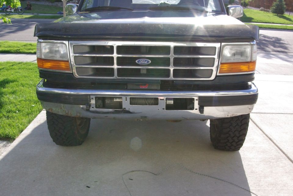 Front end of dark green Ford with chrome grille, bug deflector and hidden winch
