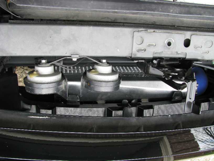 Car horns and blue hose behind vehicle grille