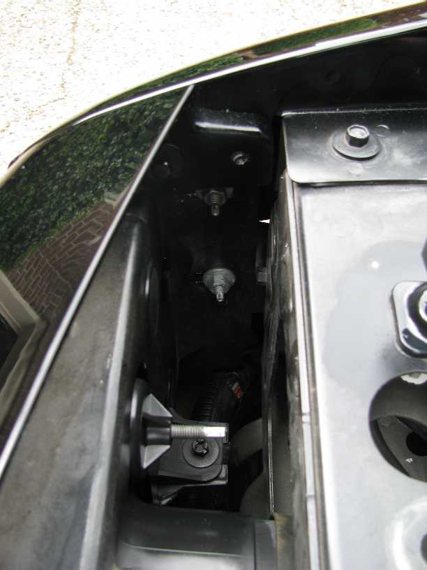 Close-up of inner fender well hardware and wiring on a black vehicle.
