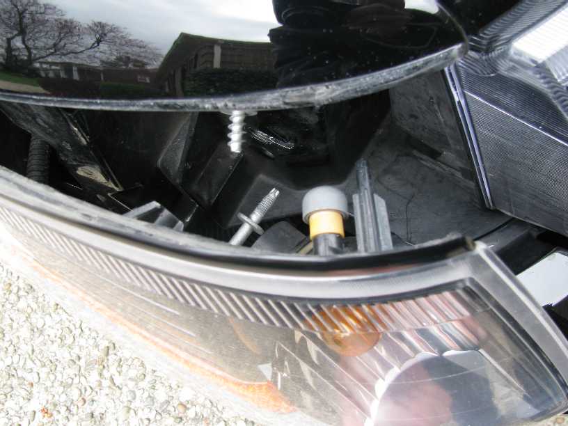 Close-up of car headlight interior with visible screw and plastic component.