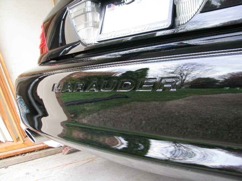 Chrome MARAUDER badge on glossy black rear bumper of sedan in garage