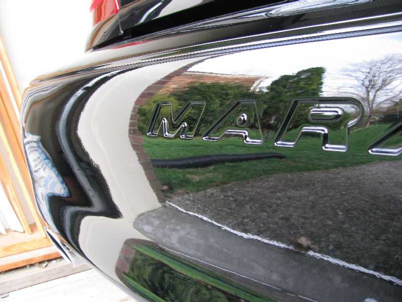 Chrome MARAUDER lettering on black rear bumper reflecting brick wall and lawn