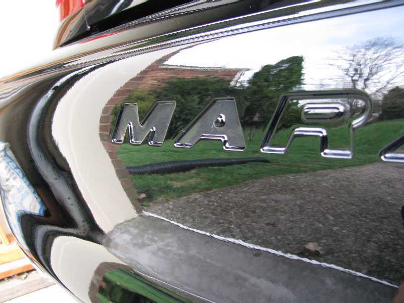 Close-up of chrome M-A-R letters on black bumper with reflections