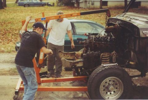 1978 Ford Bronco - Mechanics use an engine hoist to remove the engine from a vehicle, likely for repair or replacement.