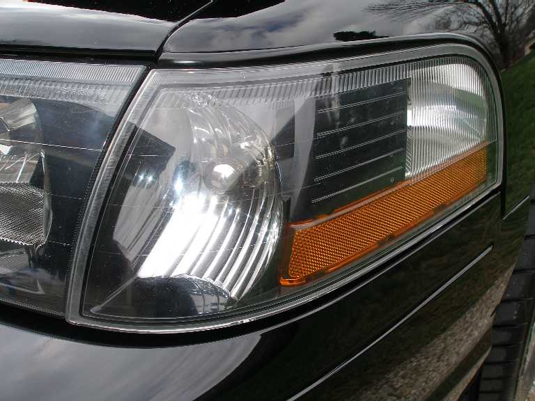 Close-up of a black car's driver side headlight with amber reflector.