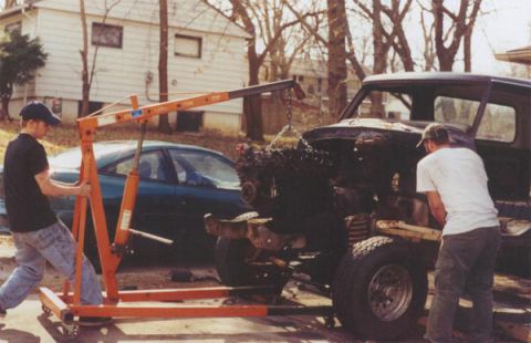1978 Ford Bronco - Engine removal in progress with an engine hoist and assistance from two people.