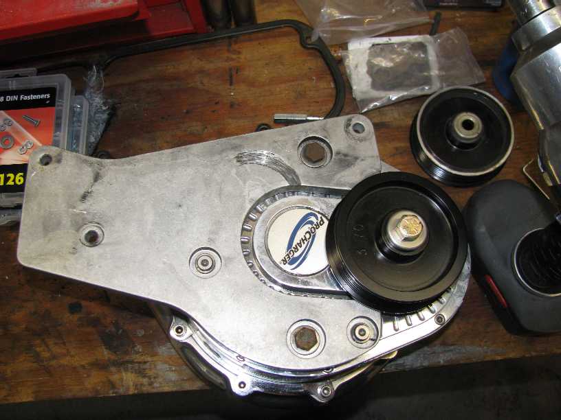 ProCharger supercharger assembly with pulleys on a wooden workbench.