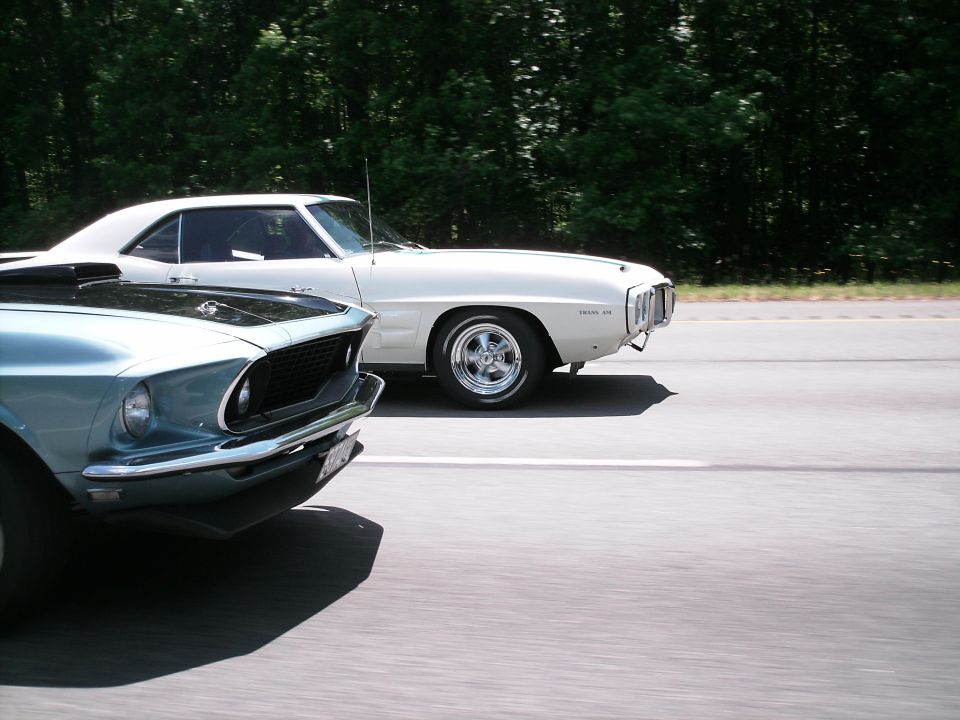Light blue and white classic cars driving on a road.