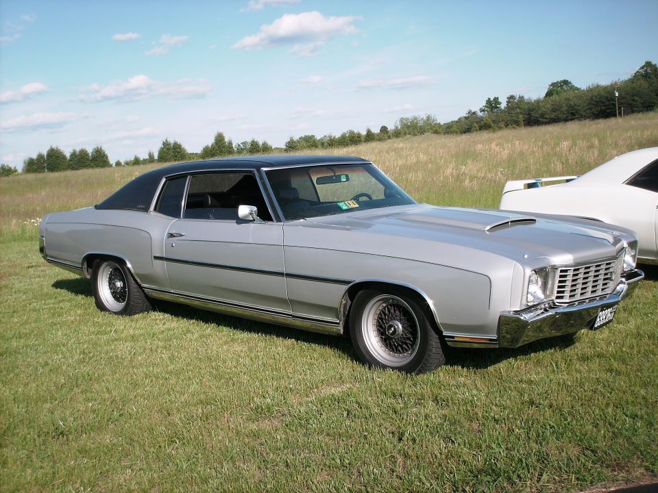 Silver coupe with black vinyl roof and wire wheels parked on grass